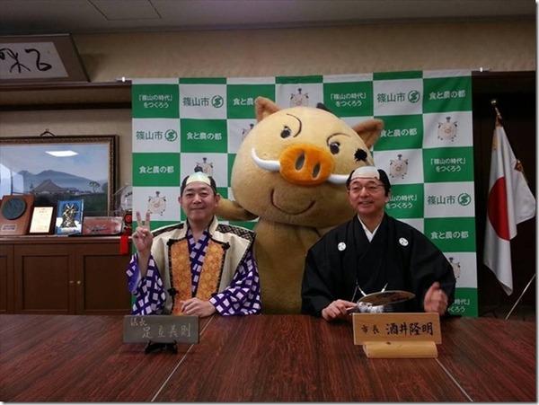 殿様姿の足立 義則議長がVサインをしており、侍姿の市長がうちわを持って座っている後ろにゆるキャラが立って記念撮影している写真